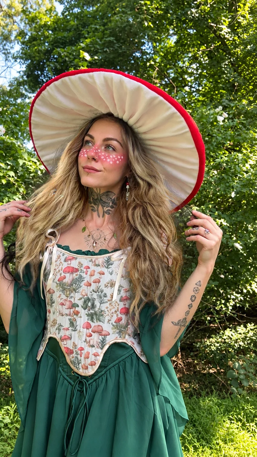 Sylvie Bloomwyn in her green dress and mushroom hat in a sunlit woodland